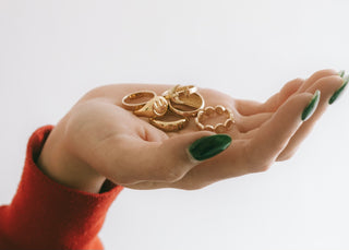Open palm holding a handful of gold plated IKAIKA rings