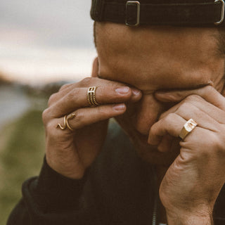 Ti Stack City ring worn: person with hands over their face wearing gold rings