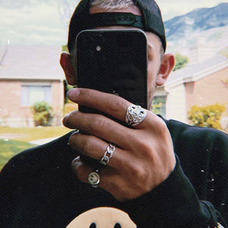 Smiley Guy ring worn: man holding a phone up to his face, wearing silver rings