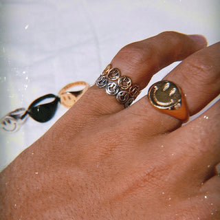 Happy Hour ring worn: hand wearing a smiley band stacked with a gold smiley signet