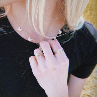 Person with blonde hair wearing thin stacking rings