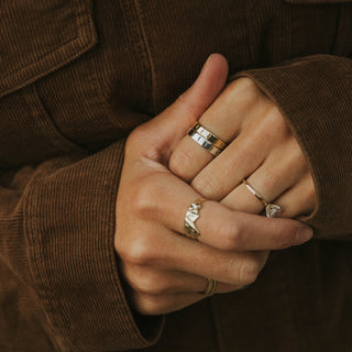 The Pines ring worn: hands clasped, wearing stacked rings