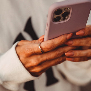 All Love ring worn: hands holding a phone, silver ring on the finger
