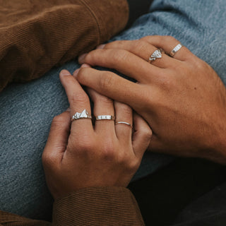 The Pines ring worn: two hands wearing silver rings, corduroy jacket