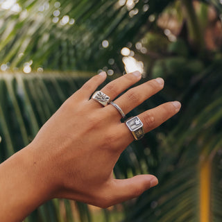 Make Waves ring worn: hand in front of palm leaves wearing rings