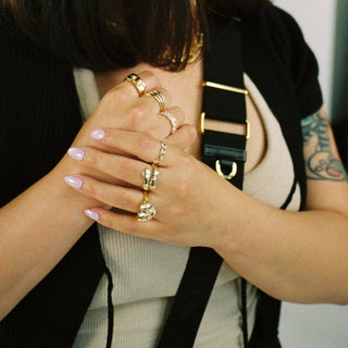 Hug Life ring worn: hands clasped, wearing stacked gold rings