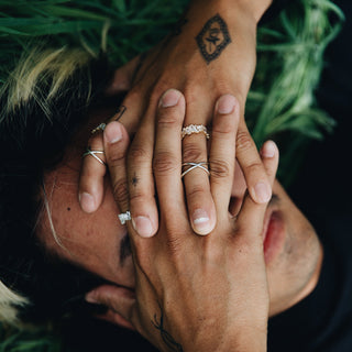 4 Ever Ever ring worn: person lying in greenery with hands over their face, wearing thin rings