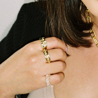 Sad Boi ring worn: hand wearing stacked gold rings with a chunky gold chain necklace