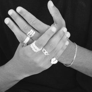 Chain Reaction ring worn: hands stacked with silver rings, black and white photo