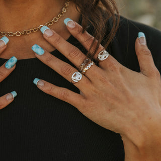 Metamorphosis ring worn: hand at the chest wearing silver butterfly rings