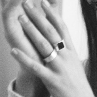 The Moment ring worn: black and white photo of a hand wearing a black stone signet