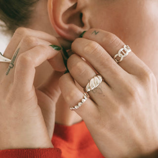 All Love ring worn: person touching their ear, wearing silver rings