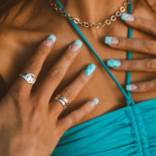 You've Changed ring worn: hands wearing silver butterfly rings against a teal top