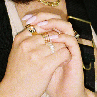 Fork Yeah ring worn: hands clasped wearing gold rings with a gold chain necklace