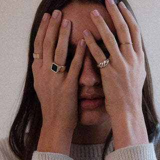 This Is Your Life ring worn: person covering their face with both hands, wearing gold rings