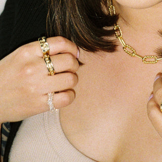 This Too Shall Pass ring worn: person wearing gold rings and a chain necklace